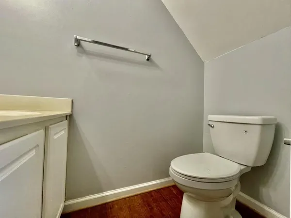 a bathroom with a toilet and a wooden floor