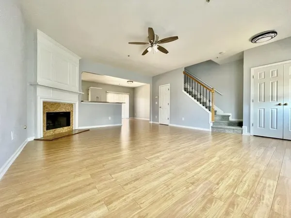 a view of an empty room with wooden floor fireplace and a window