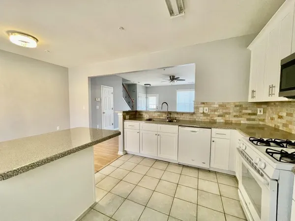 a kitchen with a sink a stove top oven and white cabinets