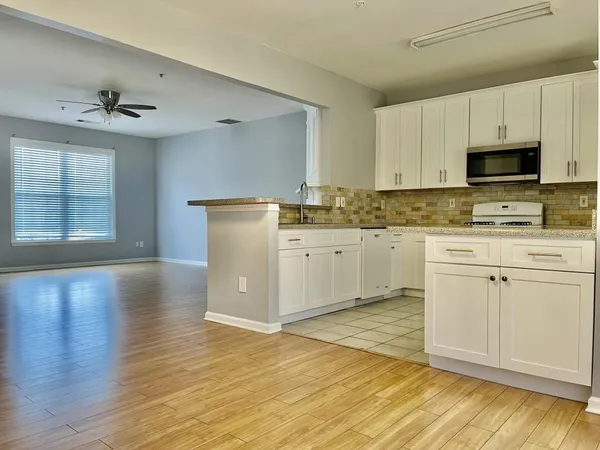 a kitchen with stainless steel appliances granite countertop a stove a sink dishwasher and a refrigerator with wooden floor