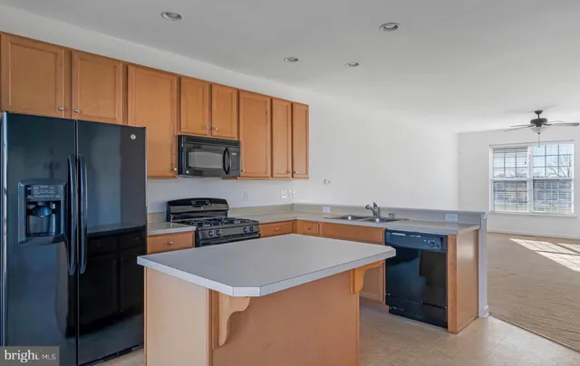 a kitchen with stainless steel appliances a stove a refrigerator a sink a stove and wooden cabinets