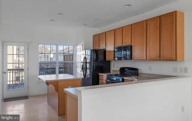 a kitchen with stainless steel appliances a refrigerator a sink a stove a microwave and wooden cabinets