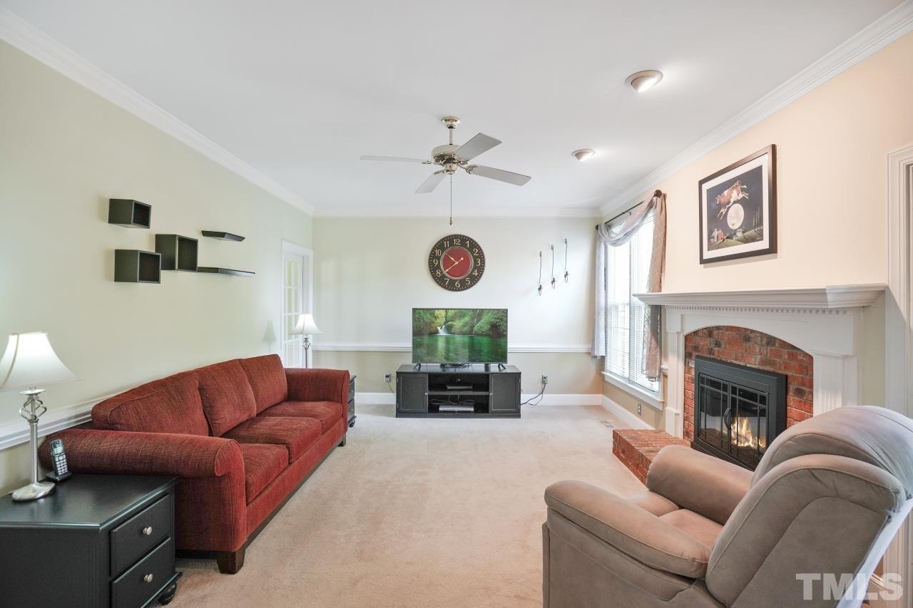 1505 Habbot Drive Raleigh, NC 27603 - Photo 11 of 32 a living room with furniture a fireplace and a flat screen tv