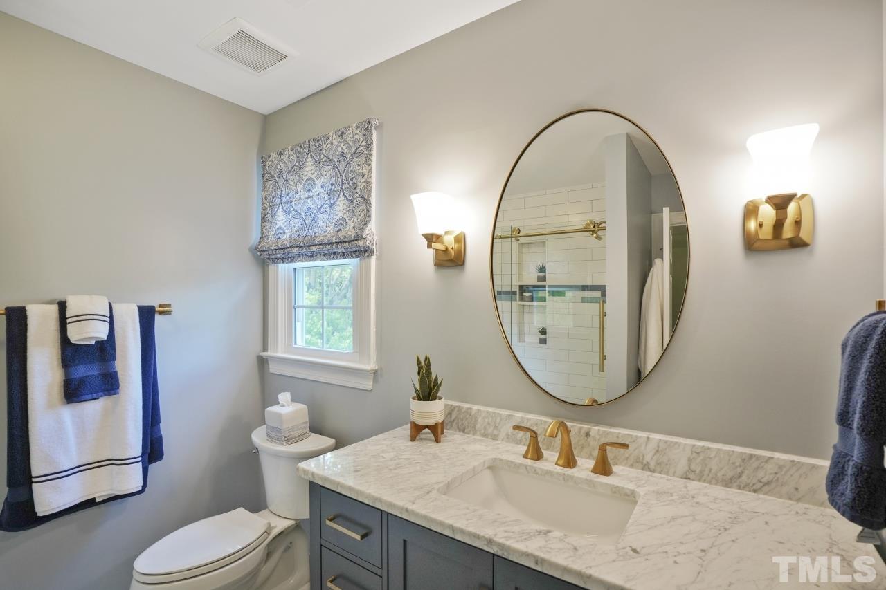 1505 Habbot Drive Raleigh, NC 27603 - Photo 22 of 32 a bathroom with a granite countertop toilet a sink and a mirror