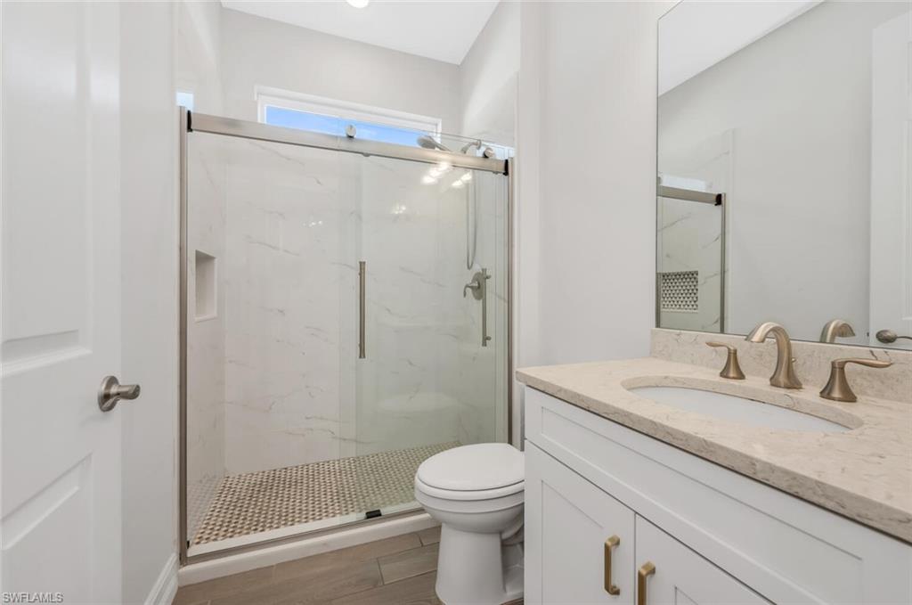 28041 Captiva Shell Loop Bonita Springs, FL 34135 - Photo 7 of 24 a bathroom with a granite countertop sink a mirror a toilet and shower