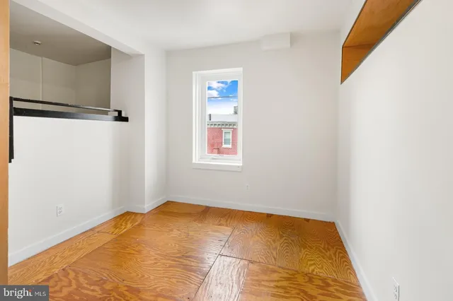 a view of a bedroom with a bed and wooden floor