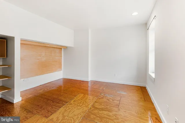 a view of an empty room with wooden floor and a bathroom