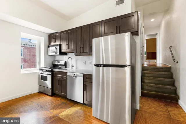 a kitchen with granite countertop a refrigerator stove and cabinets