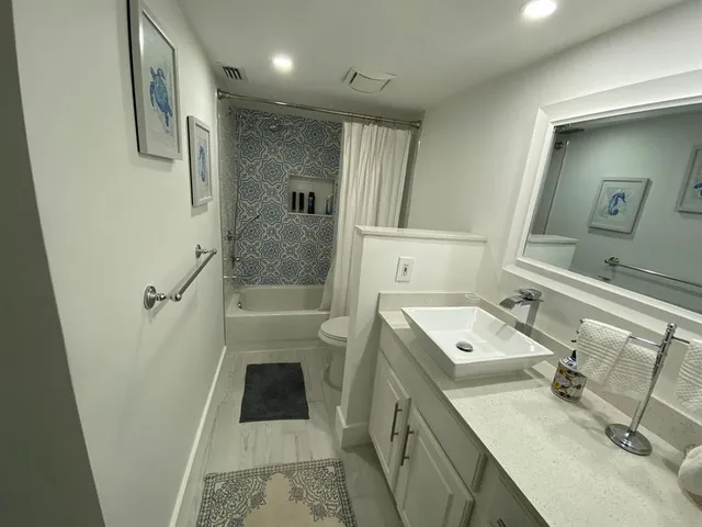 a bathroom with a sink a toilet a mirror and shower