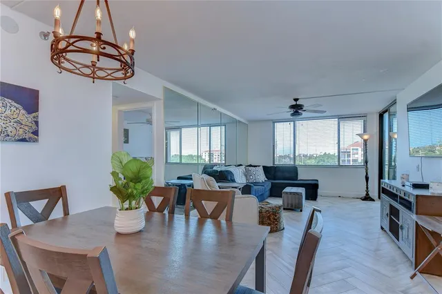 a living room with couches chandelier and a dining table with wooden floor