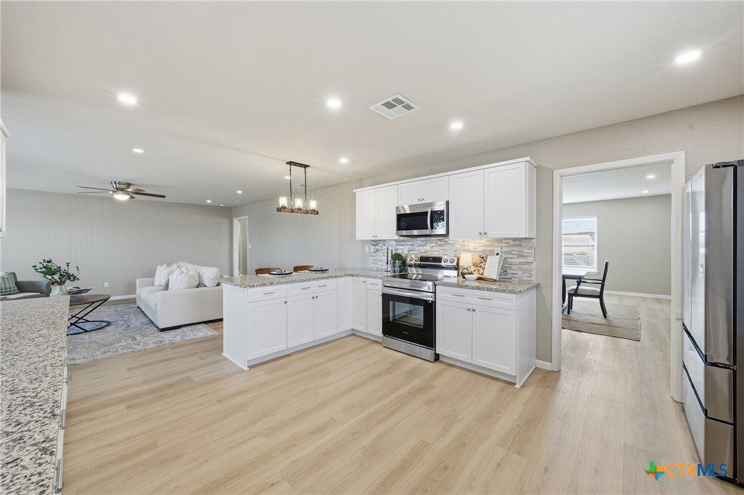 6950 Stallion Road Temple, TX 76501 - Photo 15 of 41 a large white kitchen with a refrigerator a stove top oven a sink dishwasher and white cabinets with wooden floor
