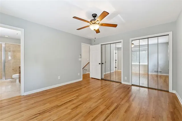 a view of an empty room with wooden floor and a ceiling fan