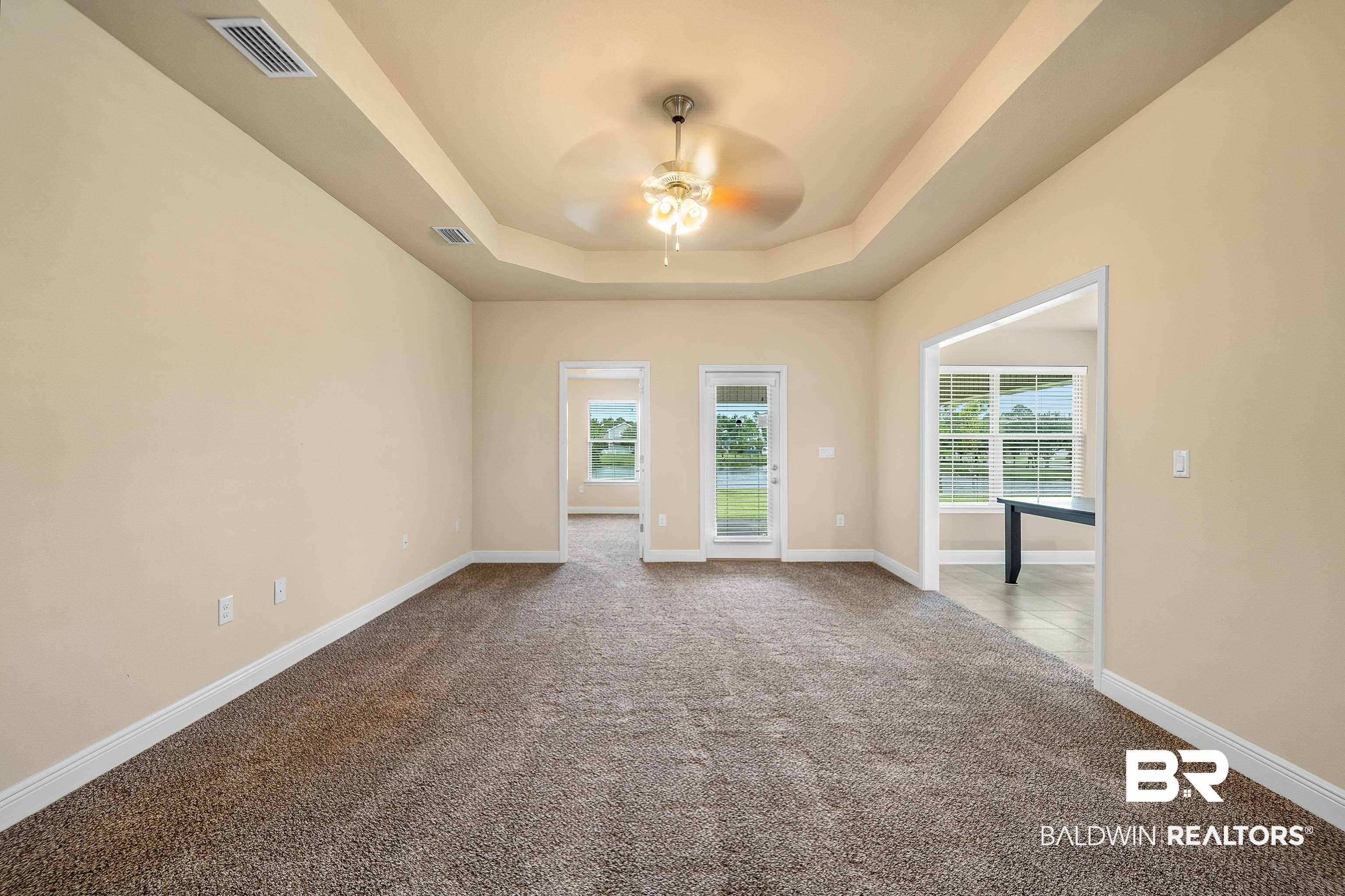 22631 Lake South Drive Foley, AL 36535 - Photo 5 of 25 Empty room with a raised ceiling, ceiling fan, and light colored carpet