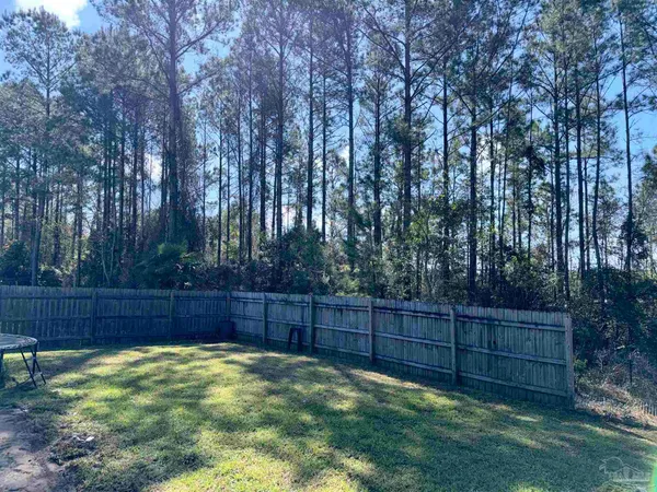 a view of backyard with wooden fence and large trees