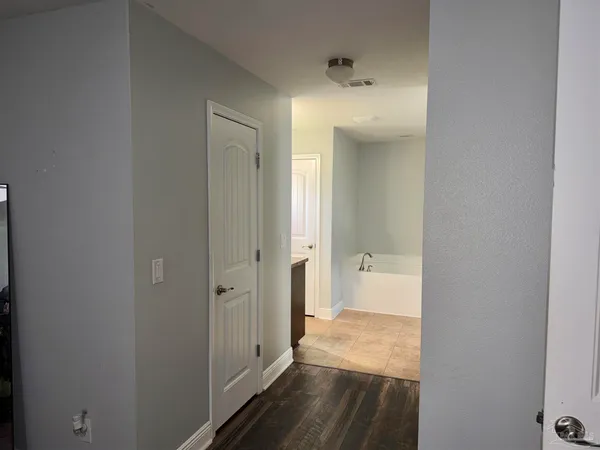 a view of a hallway with wooden floor and a bathroom