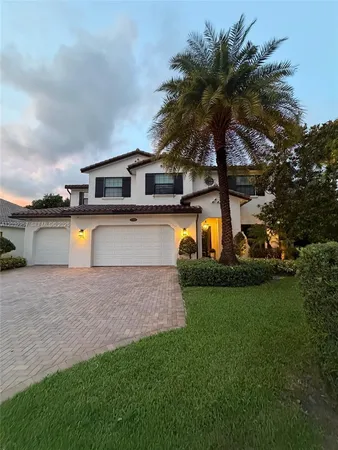 a front view of a house with a garden and lake view