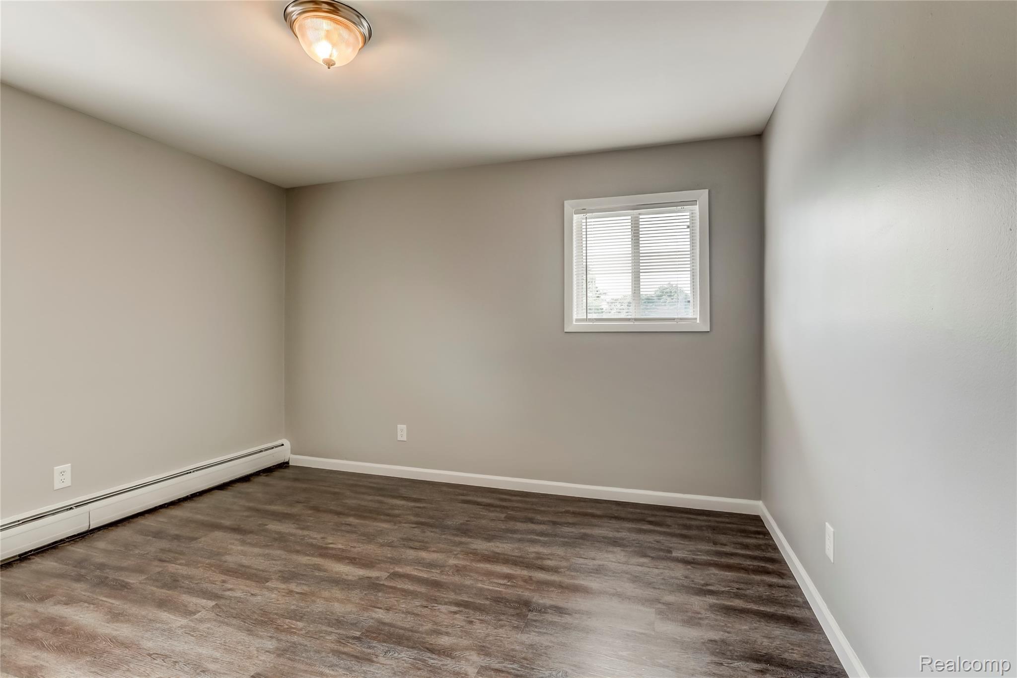 649 West Maple Road, Unit 8 Clawson, MI 48017 - Photo 8 of 16 Wood-finish flooring, neutral wall paint, and a window with blinds
