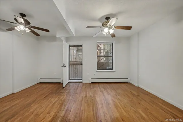a view of empty room with wooden floor and fan