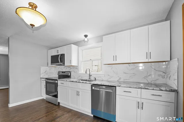 a kitchen with granite countertop white cabinets and stainless steel appliances