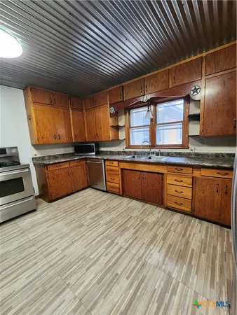 a kitchen with stainless steel appliances granite countertop a sink stove and cabinets