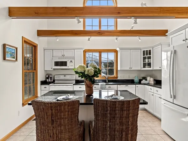 a kitchen with stainless steel appliances granite countertop a refrigerator a sink dishwasher and white cabinets next to a window