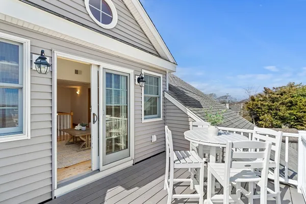 a roof deck with table and chairs and potted plants