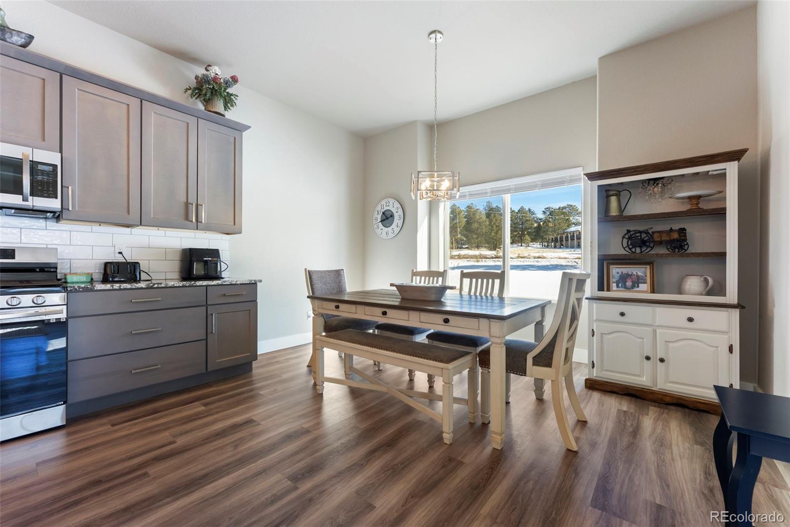 489 Duesouth Road Florissant, CO 80816 - Photo 10 of 40 a kitchen with granite countertop a stove a sink a dining table and chairs with wooden floor