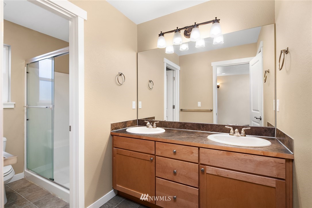 21006 42nd Avenue Southeast, Unit A Bothell, WA 98021 - Photo 13 of 19 a bathroom with a granite countertop sink a mirror and a shower