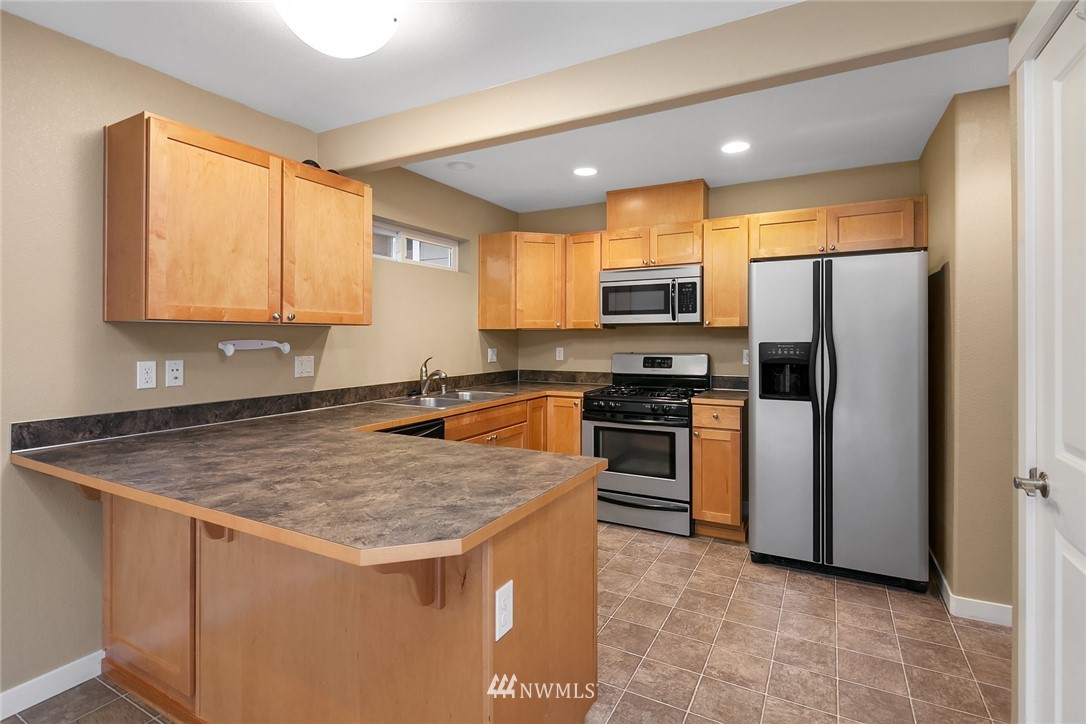 21006 42nd Avenue Southeast, Unit A Bothell, WA 98021 - Photo 7 of 19 a kitchen with stainless steel appliances granite countertop a stove a refrigerator a sink a microwave and island