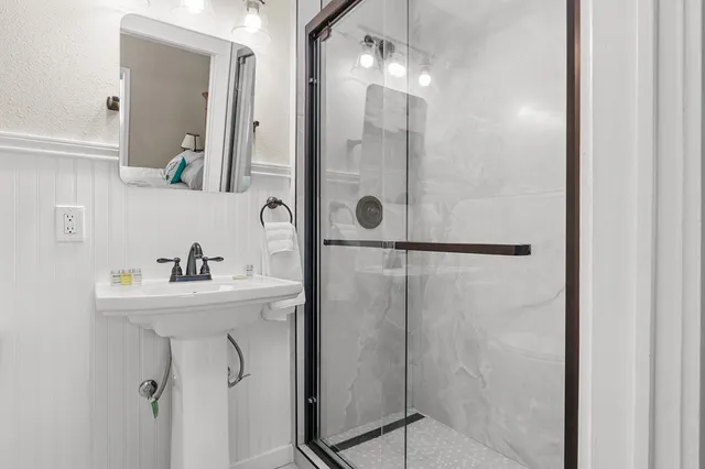 a bathroom with a sink a mirror a vanity and shower
