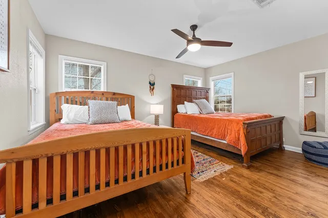 a bedroom with two beds and wooden floor