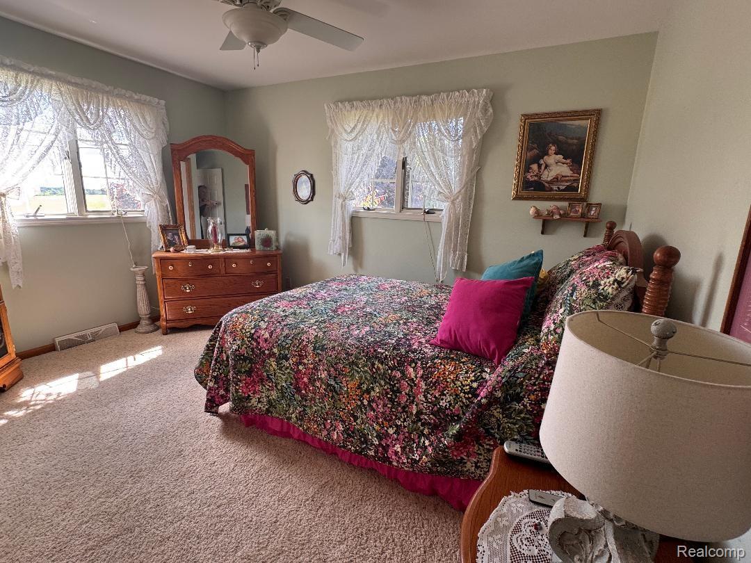 6686 South Schott Road Mayville, MI 48744 - Photo 13 of 25 Carpeted room featuring light green walls, multiple windows, a ceiling fan, and a wooden headboard
