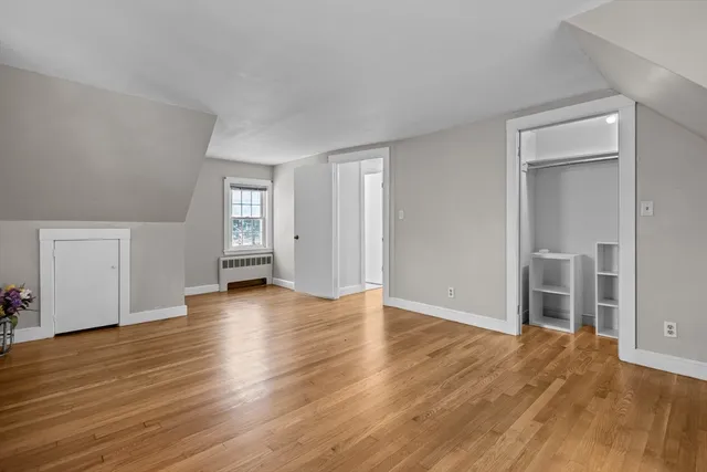 an empty room with wooden floor & windows and bathroom