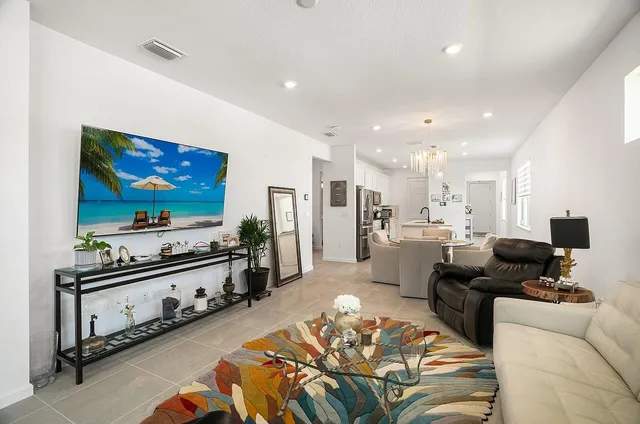 a living room with furniture a flat screen tv and a large window