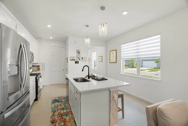 a kitchen with stainless steel appliances a sink a stove a microwave a refrigerator and cabinets