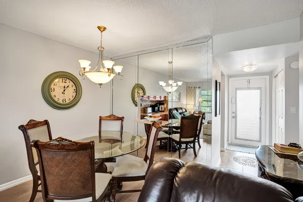 a view of a dining room and livingroom with furniture large window wooden floor and a clock