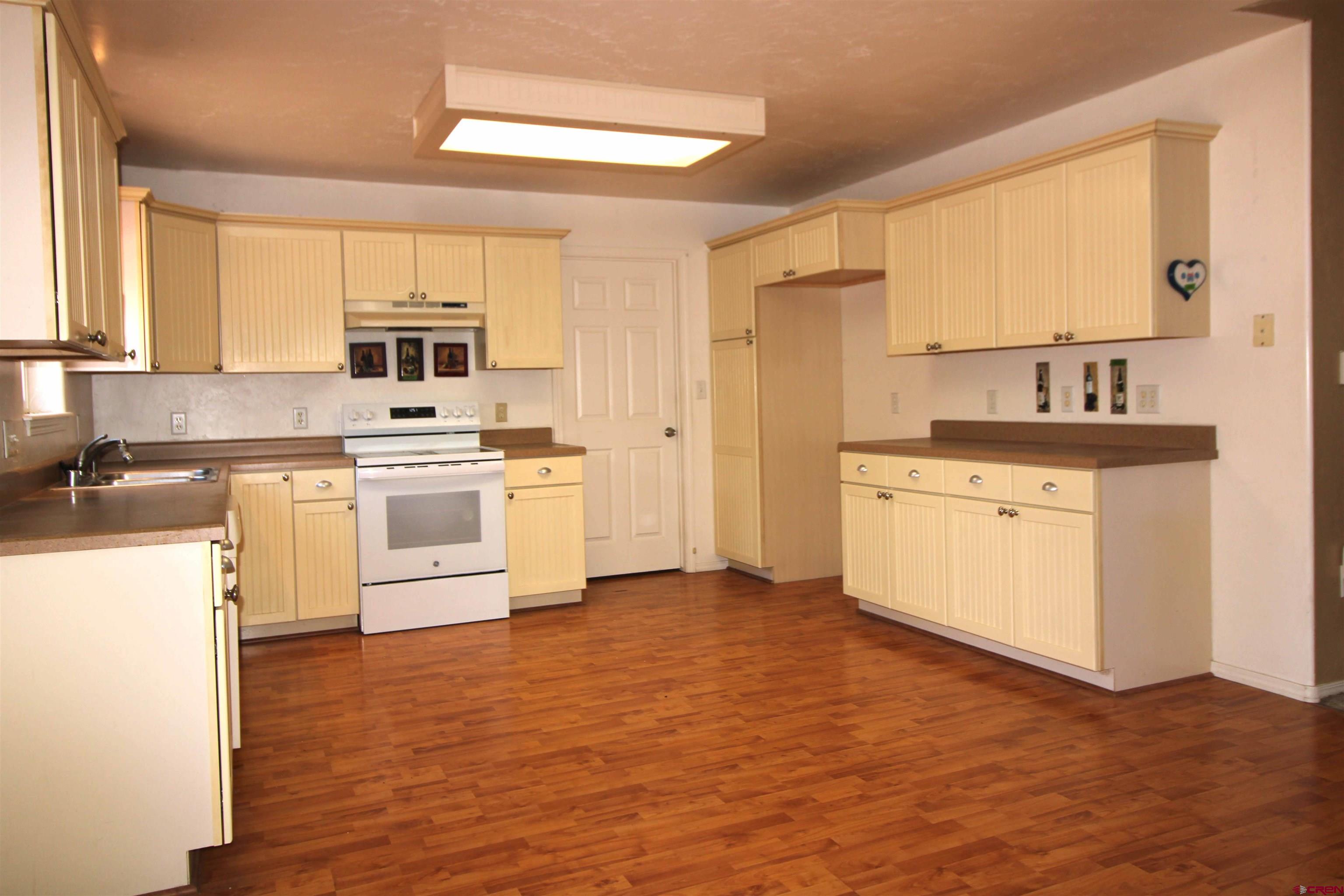 185-165 Northwest 11th Street Cedaredge, CO 81413 - Photo 12 of 34 a kitchen with a stove a sink white cabinetry and wooden floor