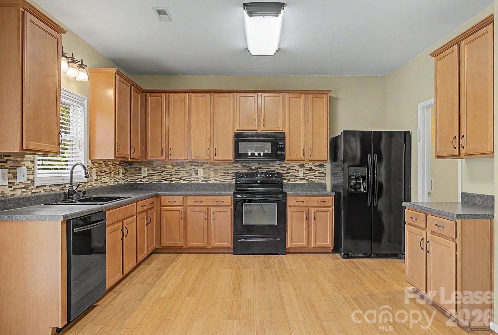 2917 Liddington Road Matthews, NC 28105 - Photo 10 of 44 a kitchen with stainless steel appliances granite countertop a stove top oven a refrigerator a sink and dishwasher with wooden floor