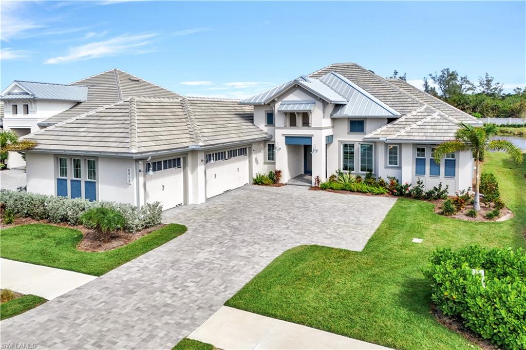 View of front of house with decorative driveway, stucco siding, an attached garage, a tile roof, and a front lawn