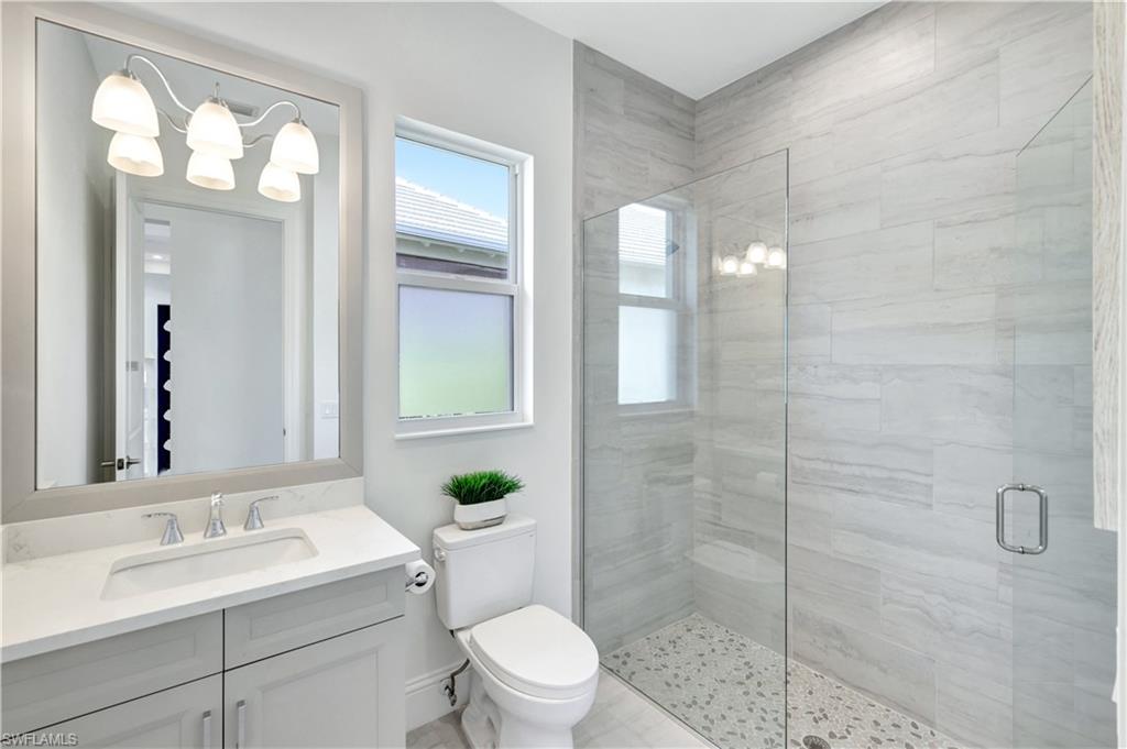 8912 Nevis Way Naples, FL 34112 - Photo 18 of 45 Bathroom featuring a stall shower, vanity, and a chandelier