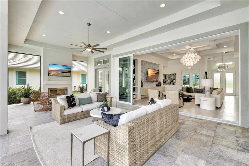 8912 Nevis Way Naples, FL 34112 - Photo 26 of 45 Living room featuring french doors, a glass covered fireplace, healthy amount of natural light, a tray ceiling, and recessed lighting
