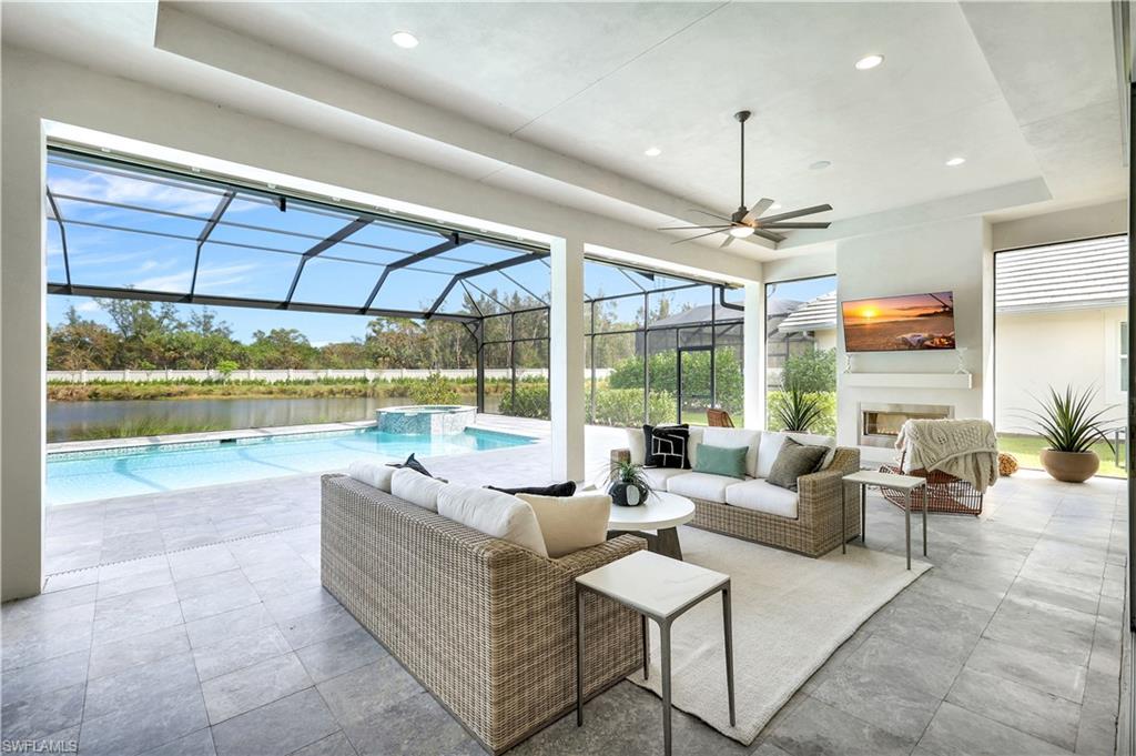 8912 Nevis Way Naples, FL 34112 - Photo 26 of 45 View of patio with a ceiling fan, a pool with connected hot tub, a sunroom, glass enclosure, and an outdoor living space with a fireplace