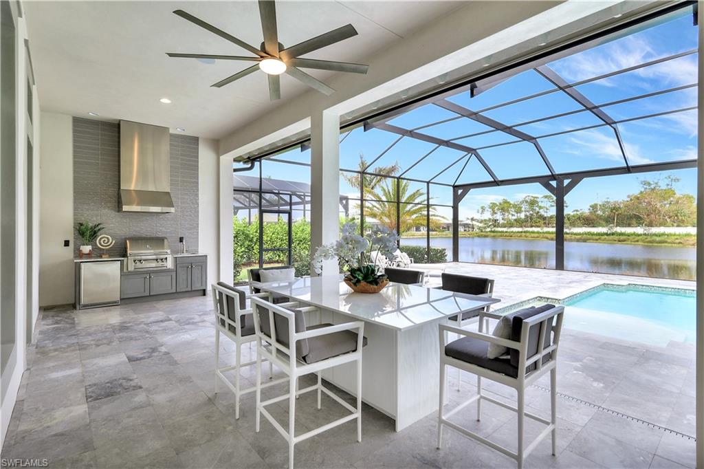 8912 Nevis Way Naples, FL 34112 - Photo 27 of 45 View of patio featuring an outdoor kitchen, a sunroom, a water view, a ceiling fan, and glass enclosure