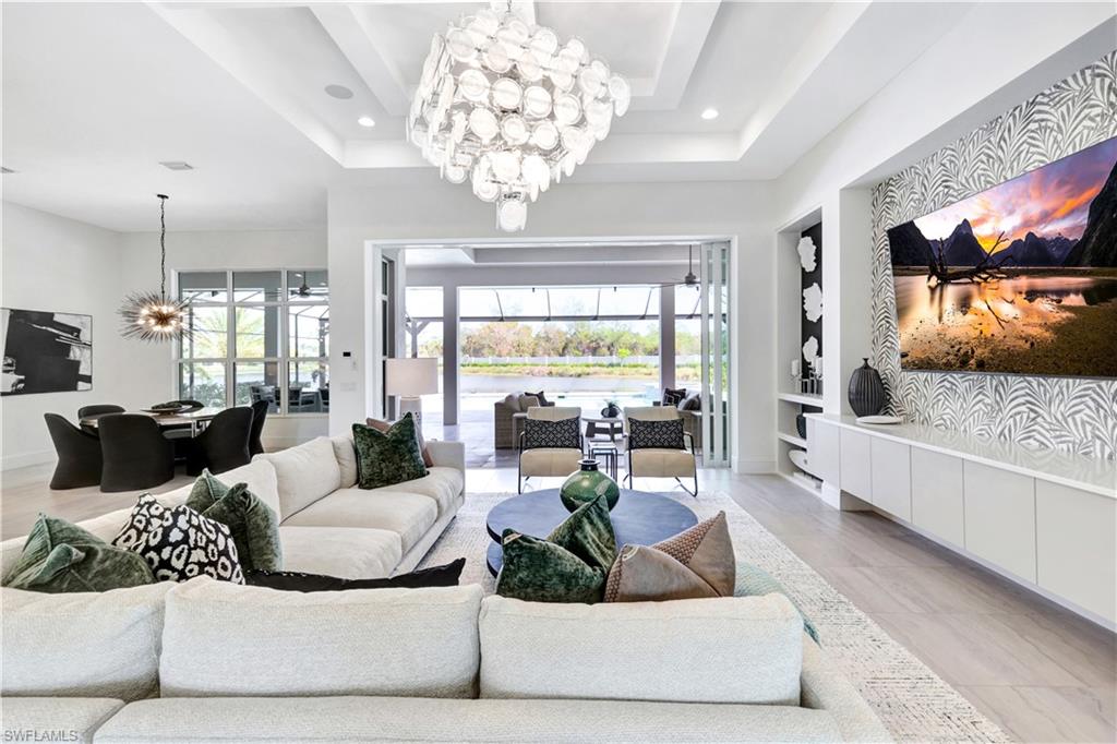 8912 Nevis Way Naples, FL 34112 - Photo 3 of 45 Living room featuring a chandelier, recessed lighting, a raised ceiling, and built in features