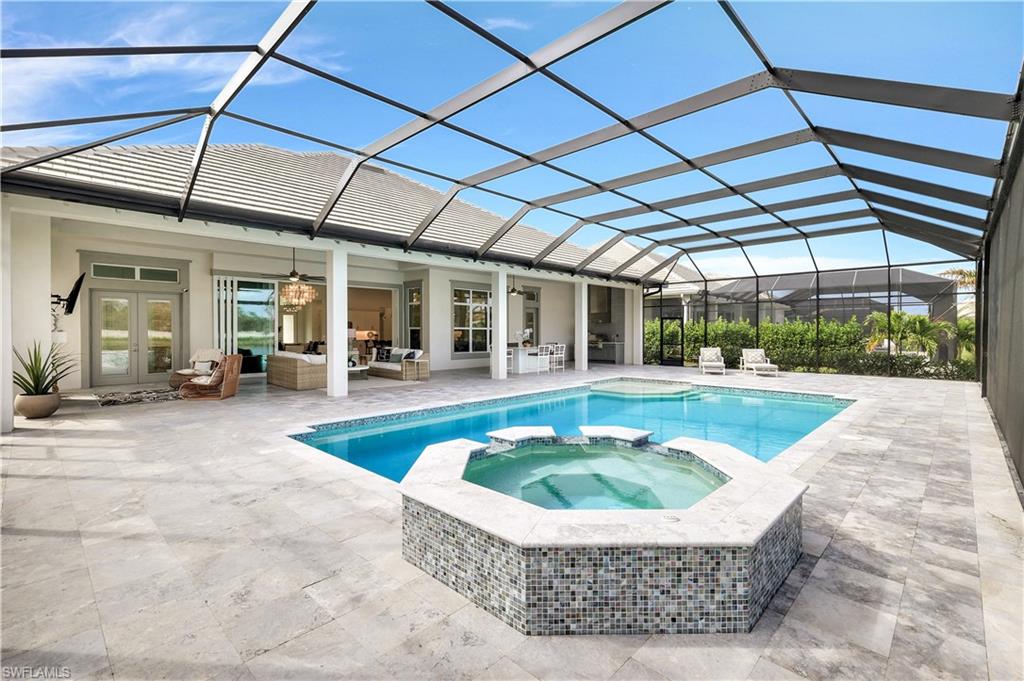 8912 Nevis Way Naples, FL 34112 - Photo 31 of 45 View of swimming pool featuring a sunroom, a pool with connected hot tub, an outdoor hangout area, glass enclosure, and a patio