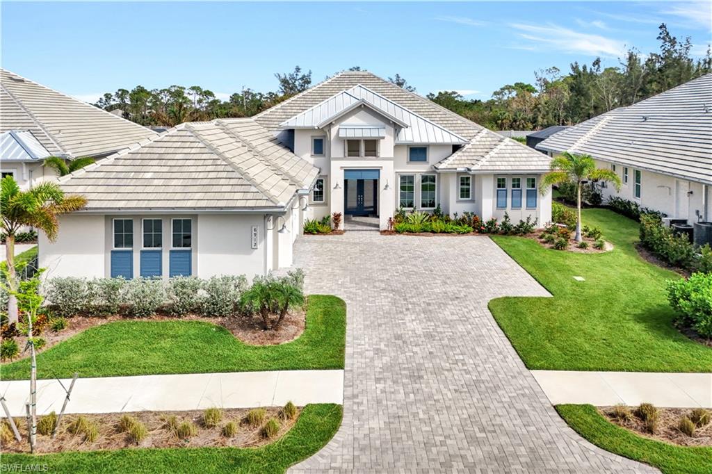 8912 Nevis Way Naples, FL 34112 - Photo 34 of 45 View of front facade with a front yard, driveway, stucco siding, and a tiled roof