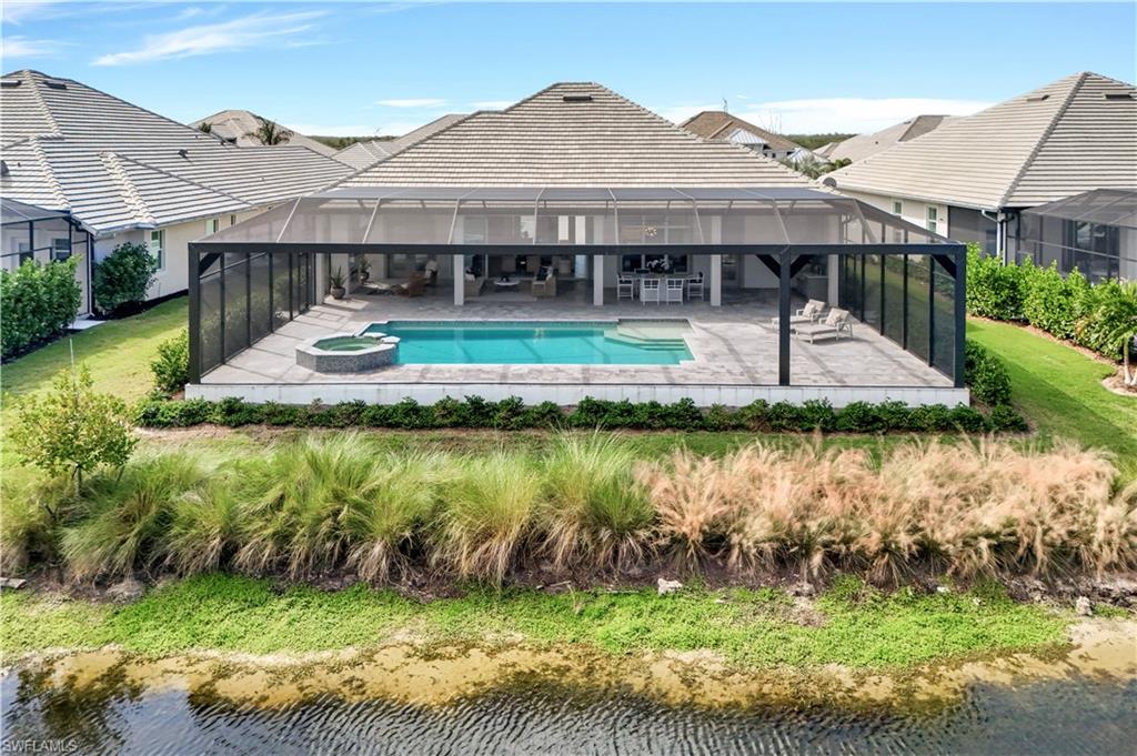 8912 Nevis Way Naples, FL 34112 - Photo 36 of 45 View of pool featuring a sunroom, a patio, a lanai, a pool with connected hot tub, and a lawn