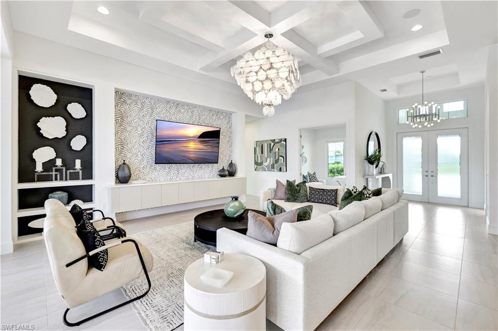 8912 Nevis Way Naples, FL 34112 - Photo 5 of 45 Living room featuring a chandelier, french doors, coffered ceiling, beamed ceiling, and a towering ceiling