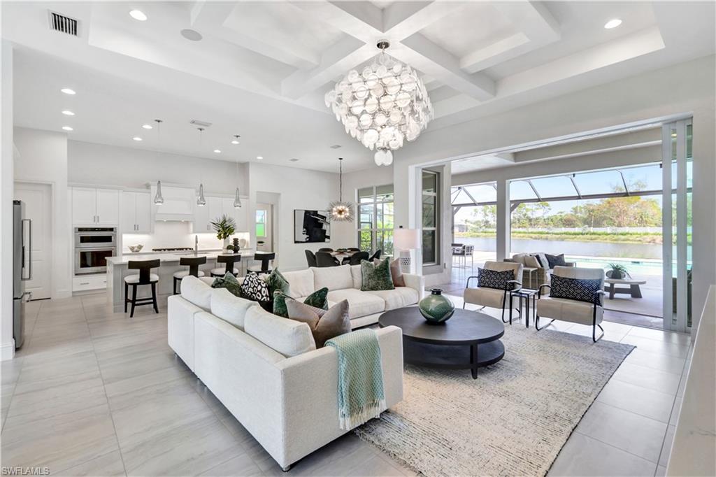 8912 Nevis Way Naples, FL 34112 - Photo 6 of 45 Living room with coffered ceiling, recessed lighting, beam ceiling, a chandelier, and a water view