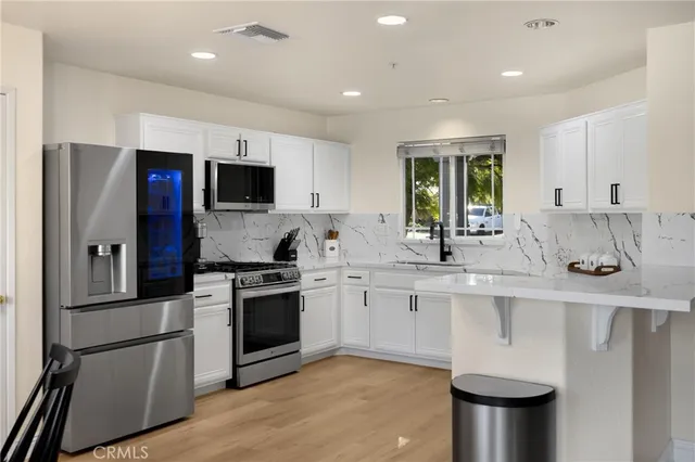 a kitchen with stainless steel appliances granite countertop a refrigerator a sink a stove a microwave and island